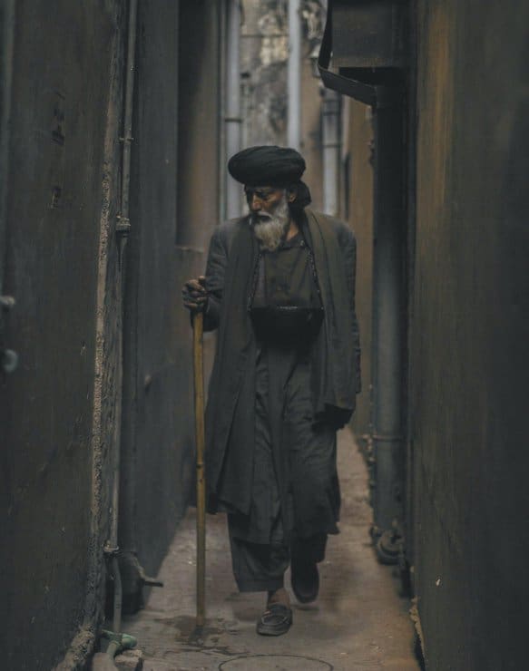 Photo of an Old Man Walking in the Alley